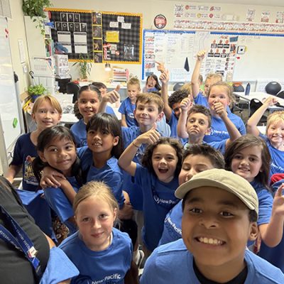 a group of elementary school students in blue shirts smiling at the camera