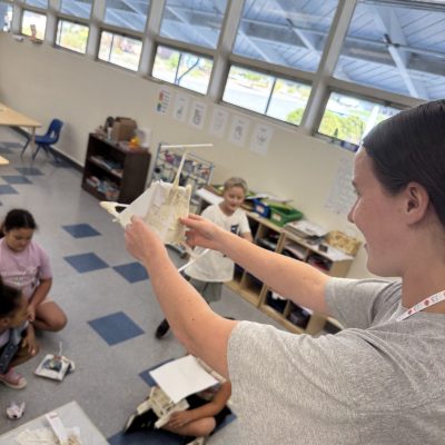 An image of a classroom, teacher demonstrating a science project for young students
